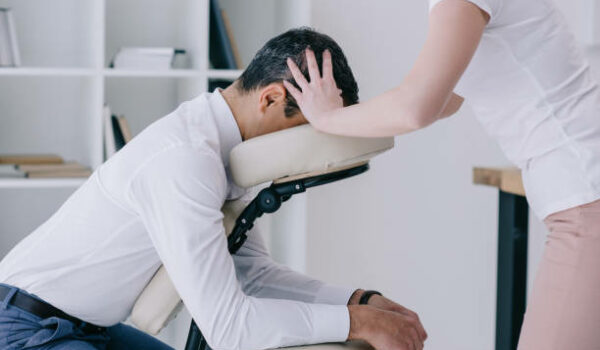 masseuse doing seated head massage for businessman