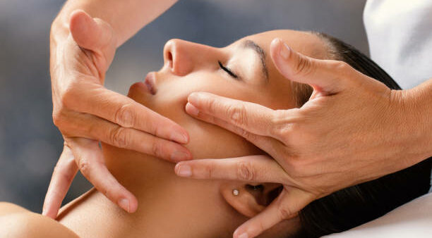 Close up portrait of woman having facial cosmetic therapy. Therapist applying cream on female cheek.